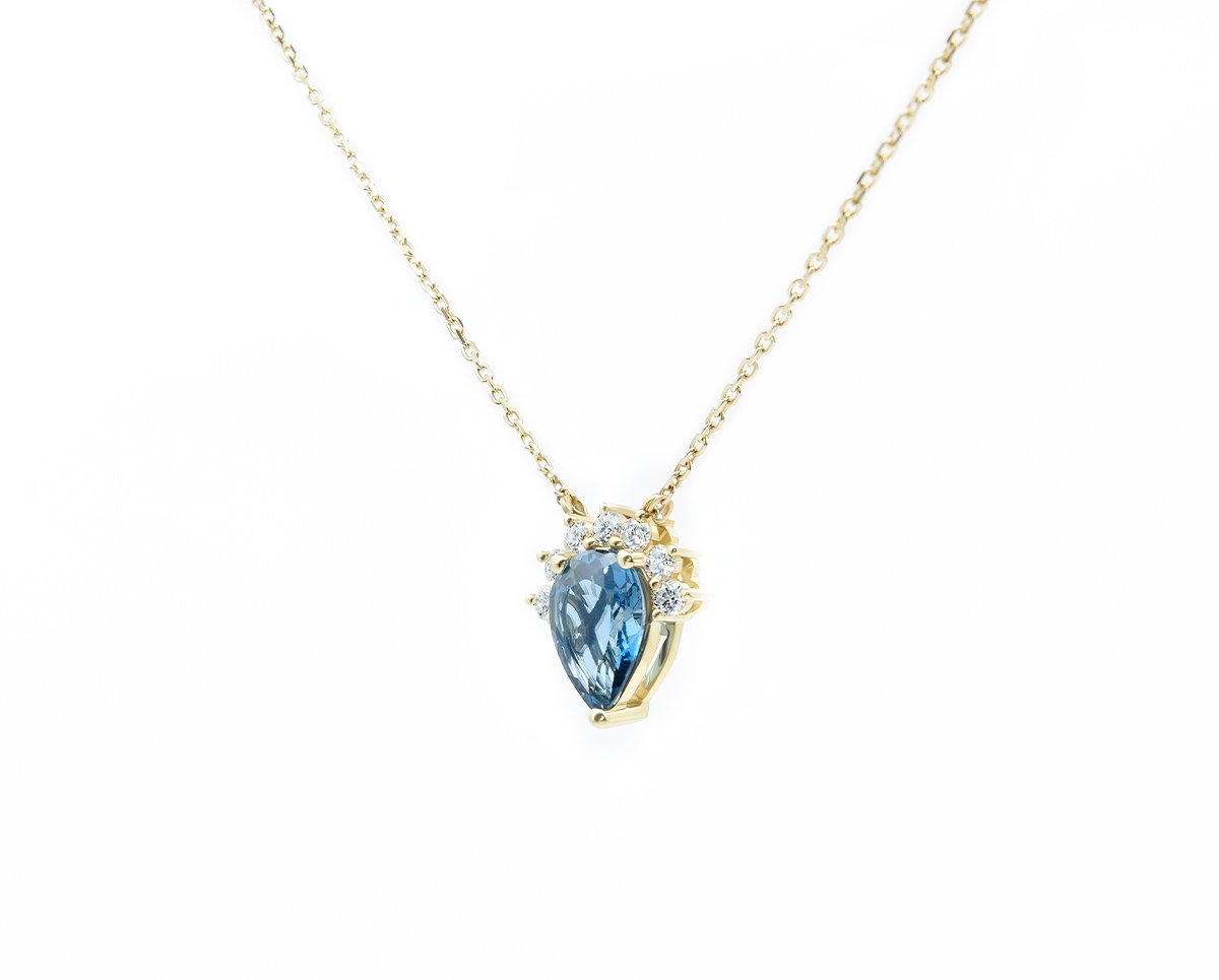 Collar Aidan Blue Oro Amarillo, o Blanco 18k, con 1 Topacio London Blue pera que suman 95 pt, más 7 Diamantes brillante que suman 14 pt, más 1 Cadena Tamaño: 11x11mm